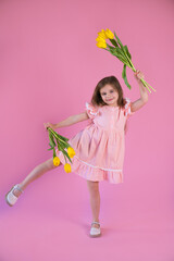 funny girl in pink dress with yellow tulips flower on pink background.