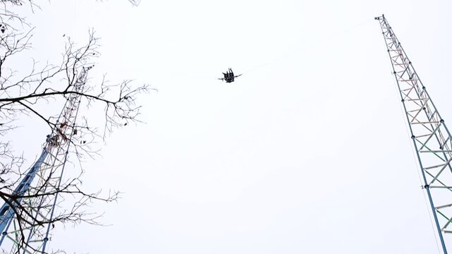 Slingshot ride capsule in park. The daring individual, loving thrills and adrenaline, attaches to the Tarzan rope and gets catapulted high into the air against a backdrop of thick clouds. 
