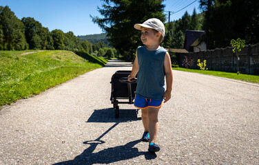 Child pulls a four-wheel folding wagon with toys and accessories during a tourist trip