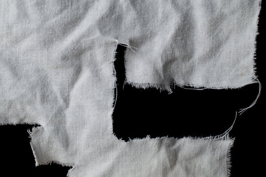 torn old white rag with holes on a black background, canvas