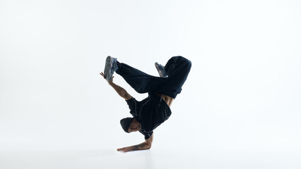 Breakdance power move freeze with extended legs isolated on white background. Concept of youth culture marketing, dynamic motion graphics sources and sports performance visuals.
