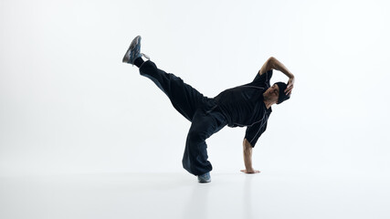 Male dancer performing dynamic floor level movement in studio. Concept of professional dance training promotion, fitness program advertising and performance focused visual content.