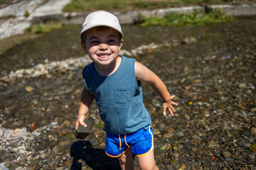 Delighted child smiles while having fun in a mountain stream