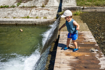 Child walks near a waterfall on a mountain stream, vacation time in the mountains during the summer