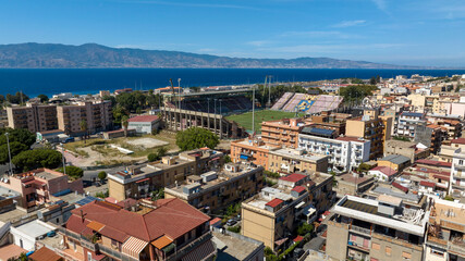 Fototapeta premium Aerial view of the football stadium located in Reggio Calabria, southern Italy. In the background, across the Strait of Messina, Sicily can be seen, separated by the sea.