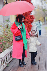 Mom and daughter with an umbrella on an autumn walk in the city outside