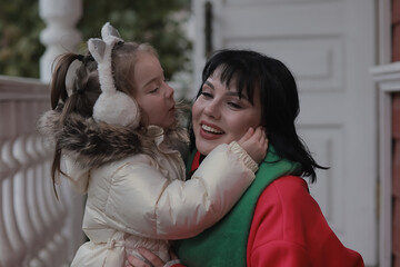 Daughter hugs and kisses mom in autumn look outside