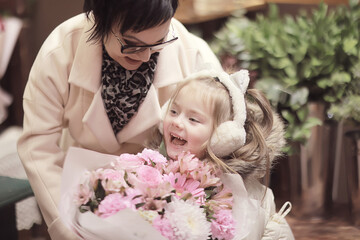 A girl and her grandmother choose and buy a bouquet of flowers at a flower shop, an autumn or spring holiday greeting