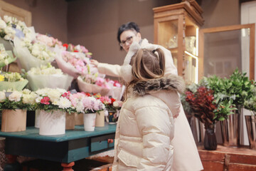 A girl and her grandmother choose and buy a bouquet of flowers at a flower shop, an autumn or spring holiday greeting