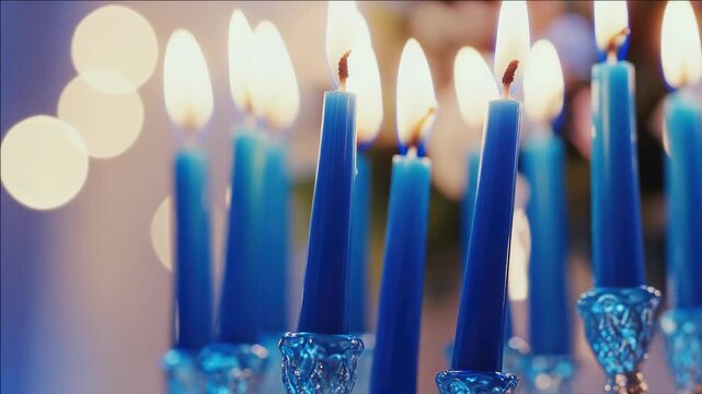 A grouping of seven lit candles with reflections on the glass