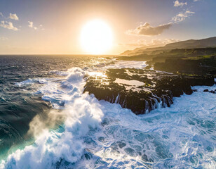 Breathtaking aerial vista of powerful ocean waves crashing against dark volcanic rocks during a golden sunset. Capturing the raw energy and serene beauty of natures coastal majesty.