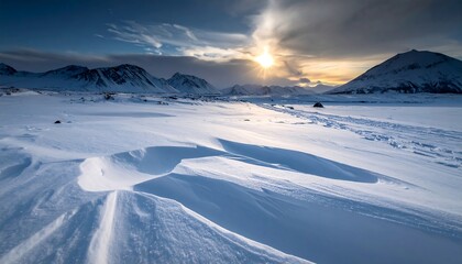 Snowy landscape with mountains and a bright sun.