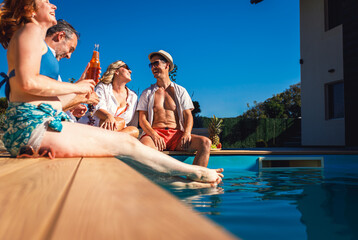 Group of middle aged friends enjoying fruit and drinks by swimming pool.