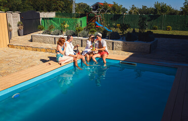 Group of middle aged friends enjoying fruit and drinks by swimming pool.