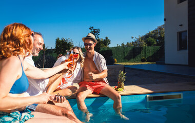 Group of middle aged friends enjoying fruit and drinks by swimming pool.