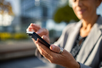 Businesswoman using smartphone outdoors in city