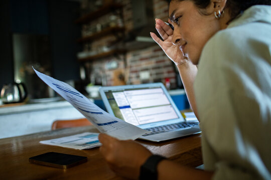 Young adult reviewing household bills at kitchen table