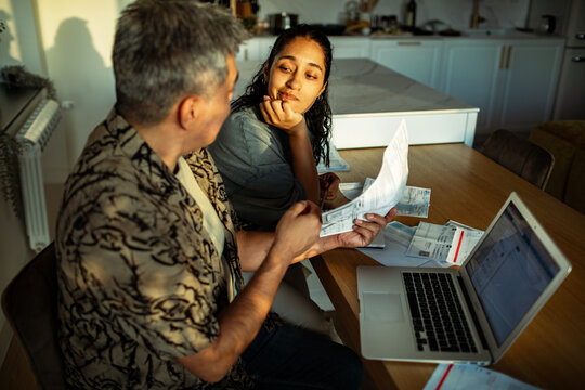 Couple reviewing bills and finances at home kitchen table