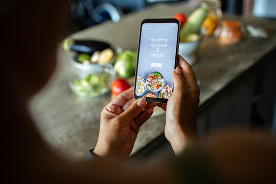 Person using recipe app on smartphone in home kitchen