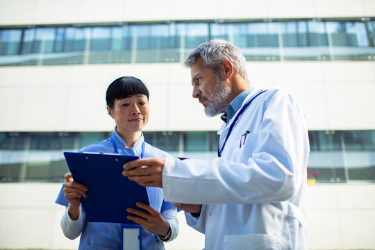 Doctor and nurse reviewing chart outside hospital