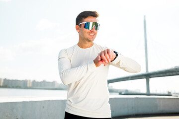 Young man checks fitness watch by the river