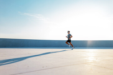 Man runs on rooftop during a bright day
