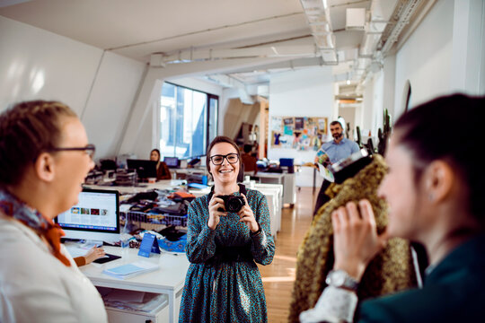 Young photographer shooting colleagues in fashion design studio