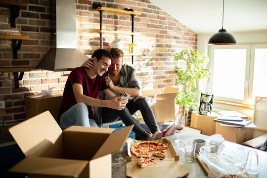Happy couple eating pizza while moving into a new kitchen