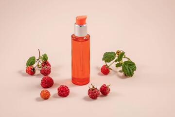 bottle of collagen or essential oil and raspberry berries on a pink background