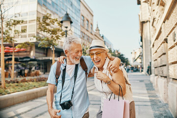 Happy senior couple shopping and sightseeing in city