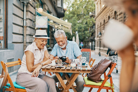 Senior couple reviewing photos at a city sidewalk cafe