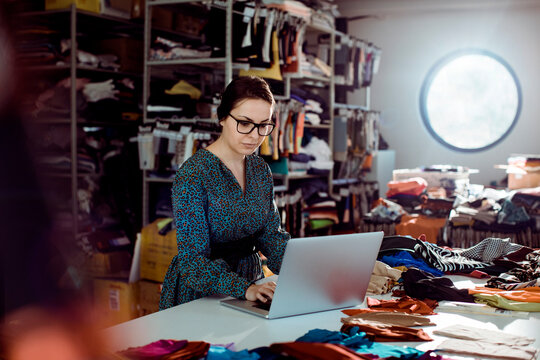 Female small business owner using laptop in fabric studio