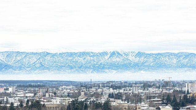 Winter panoramic view of Kutaisi, Georgia with snow-covered rooftops and Caucasus Mountains - Powered by Adobe