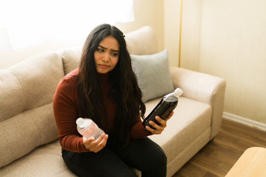 Woman making difficult healthy lifestyle choice between refreshing bottled water and unhealthy sugary soda drink