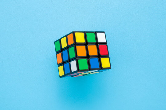 Colorful plastic rubik cube on light blue table background. Pastel color. Closeup. Top down view.