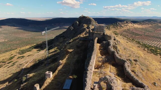 Drone descends while the camera tilts upward, showing the castle&rsquo;s long, ship-like form, its position on the rocky peak and the main tower under restoration.