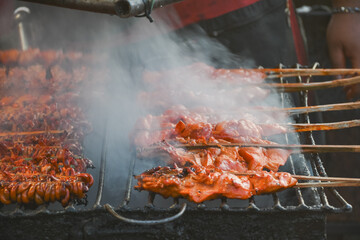 Grilled chicken on bamboo skewers served on banana leaves.