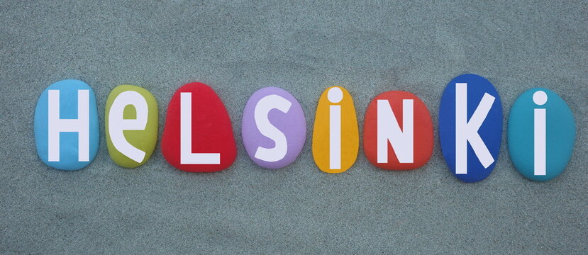 Helsinki, capital city of Finland, creative logo design composed with hand painted multi colored stone letters over green sand 