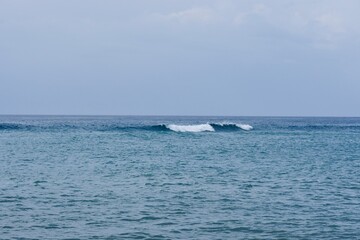 Fototapeta premium Minimalist seascape with a single breaking wave in the deep blue ocean
