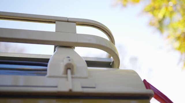 A white rack is on top of a vehicle. The rack is attached to the vehicle and is used to carry items