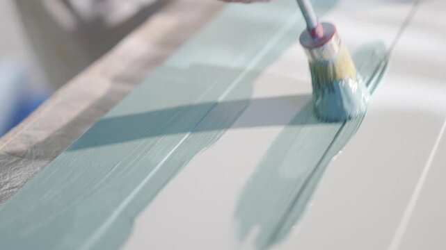 A blue and white stripe is painted on a surface. The blue stripe is the dominant color, and the white stripe is thin and barely visible. The painting appears to be a work of art, with the blue