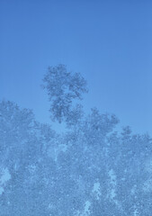 frost pattern on window glass background texture close up view with clear blue sky 