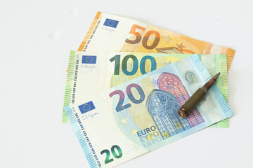 Obraz premium Euro banknotes and bullets on a white background, concept of arms trade, war.