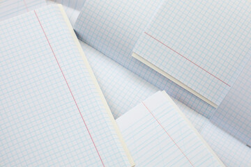 Several open school notebooks in grid and ruled styles are layered on top of each other, forming a light paper composition. Snow-white pages with clear margins and lines are ready for use,