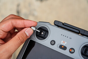 A hand carefully inserting a small metallic connector into the port of a modern drone controller...