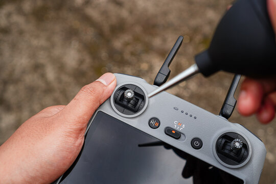 Close-up of hands adjusting controls on a drone remote controller with a screwdriver being used to tighten or loosen a component on the device indicating maintenance or setup in progress.