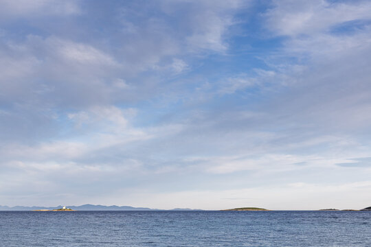 Serene Seascape With Calm Ocean And Distant Islands and Lighthouse Under Clear Blue Sky, Orebic, Croatia
