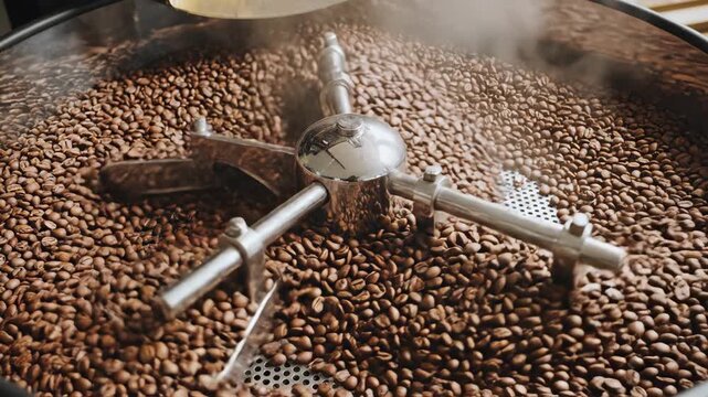 Coffee Beans Roasting in Industrial Machine with Silver Agitator and Ambient Lighting Showing Steaming Effect and Detailed Brown Roasted Coffee Beans