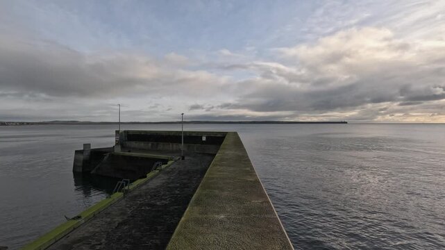 POV walking along concrete breakwater at Tramore Ireland ocean pier