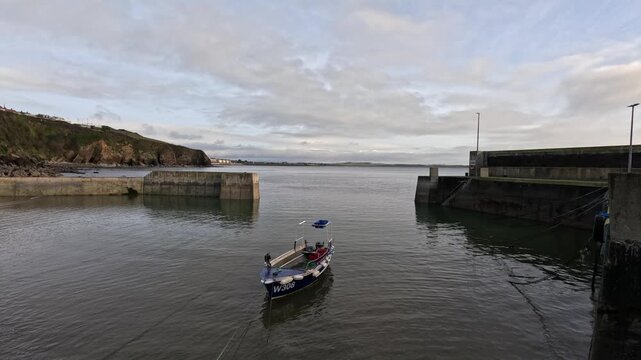One lone boat is moored behind tall concrete breakwater at ocean pier